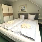 Schlafzimmer mit Doppelbett, Kleiderschrank und Nachttischen unter Dachschrägen.