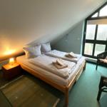 Zimmer mit Doppelbett, Sitzgelegenheit und großem Fenster