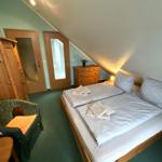 Schlafzimmer mit Doppelbett, Holzmöbel und schräger Decke.