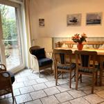 Esszimmer mit Holztisch, Stühlen und Blick auf Balkon