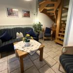 Wohnzimmer mit Sofa, Sessel und Holztreppe.