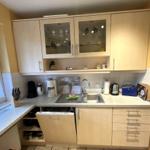 Küche mit hellen Schränken, Spüle und Fenster