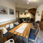 Esszimmer mit Holztisch, Bänken und Küchenzeile