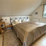 Schlafzimmer mit Dachschrägen, Bett, Nachttisch und Fenster.