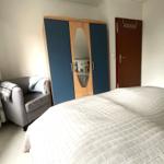 Schlafzimmer mit Bett, Kleiderschrank und Sessel.