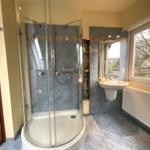 Badezimmer mit Dusche, Waschbecken und Fenster