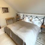Schlafzimmer mit Dachschrägen, Bett, Nachttischen und Schreibtisch.