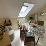 Esszimmer mit Esstisch, Stühlen und Dachfenster. Wandspiegel und Pflanzen sichtbar.