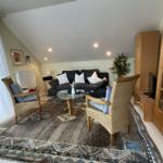 Wohnzimmer mit Sofa, zwei Sesseln und Glas-Tisch auf Teppich
