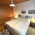 Schlafzimmer mit Bett, Nachttischen und Wandbildern