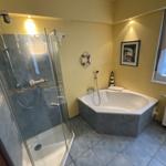 Bad mit Dusche und Badewanne, gelbe Wände, Fenster mit Vorhang.