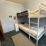 Zimmer mit Doppelstockbett, Nachttisch und Teppich auf Teppichboden.