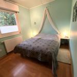 Schlafzimmer mit Bett, Fenster und Holzboden.