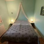 Schlafzimmer mit Bett, Baldachin, zwei Nachttischen und Wandbild.