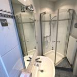 Badezimmer mit Dusche, Waschbecken und Spiegel