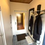 Eingangsbereich mit Garderobe, Schuhe und Tür zum Haus.