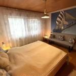 Schlafzimmer mit Bett, Sofa und Wandbild eines Segelschiffs.