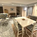 Esszimmer mit weißem Tisch und Stühlen, Sofa und Fenster mit Vorhängen.