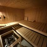 Holzsauna mit mehreren Sitzbänken und Steineinsatz.