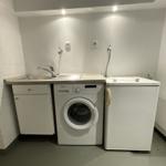 Wäscherei mit Waschmaschine, Spülbecken und Kühlschrank.