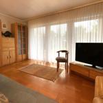 Wohnzimmer mit Holzmöbeln, Fernseher und großem Fenster