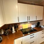 Küche mit weißen Schränken, Holzoberflächen und Induktionskochfeld.