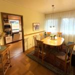 Esszimmer mit Holztisch, Stühlen und Blick in die Küche.