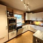 Küche mit weißen Schränken, Edelstahlgeräten und Holzboden.