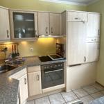 Küche mit hellen Schränken, Arbeitsplatte und Fenster