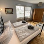 Zimmer mit Doppelbett, Holzmöbel und Fenster mit Blick auf Schnee.