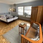 Zimmer mit Bett, Sofa, Holzschrank und Fenster mit Blick nach draußen.