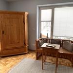 Ein Raum mit Holzschrank, Sitzbank und Tisch vor Fenster mit Jalousie.