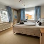 Schlafzimmer mit Doppelbett, Fenstern und Holzmöbeln.