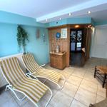 Zwei Liegestühle, Holzschrank und Tür in einem Raum mit hellblauen Wänden.