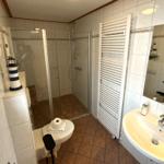 Badezimmer mit Dusche, Waschbecken und Heizkörper