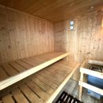 Sauna mit Holzbank, Holzwand und Heizung.