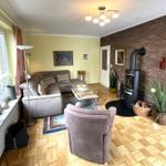 Wohnzimmer mit Sofa, Sessel, Kaminofen und Holzboden.