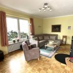 Wohnzimmer mit Sofa, Sessel, Fernseher und Kaminofen.