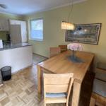 Essbereich mit Holztisch, Stühlen und Fenster. Küche mit Arbeitsplatte und Schränken.