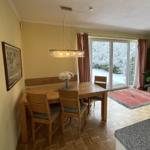 Esszimmer mit Holztisch, Stühlen und Blick auf Schnee. 