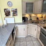 Küche mit hellen Schränken, Granitplatte und Edelstahlspüle.