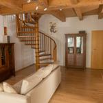 Wohnzimmer mit Holzdecke, Spiral-Treppe und Sofa.