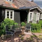 Schwarzes Holzhaus mit grüner Tür und Gartenmöbeln auf Kies