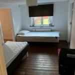 Zimmer mit zwei Betten, Holzboden und Fenster mit Rollladen.