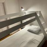 Hochbett mit Matratze und Kissen, integrierte Treppe und Stehlampe.