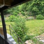 Vor dem Haus befindet sich ein grüner Garten mit Bäumen und einem Steigweg.