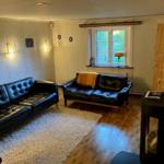 Wohnzimmer mit zwei Ledersofas, Holzboden und Fenster mit Blick auf Grün.