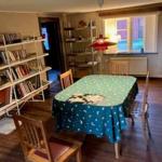 Esszimmer mit Tisch, Stühlen und Bücherregal an der Wand.