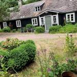 Schwarzes Holzhaus mit grüner Tür und Gartengrundstück.