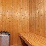 Sauna with wooden walls, bench, and heater.